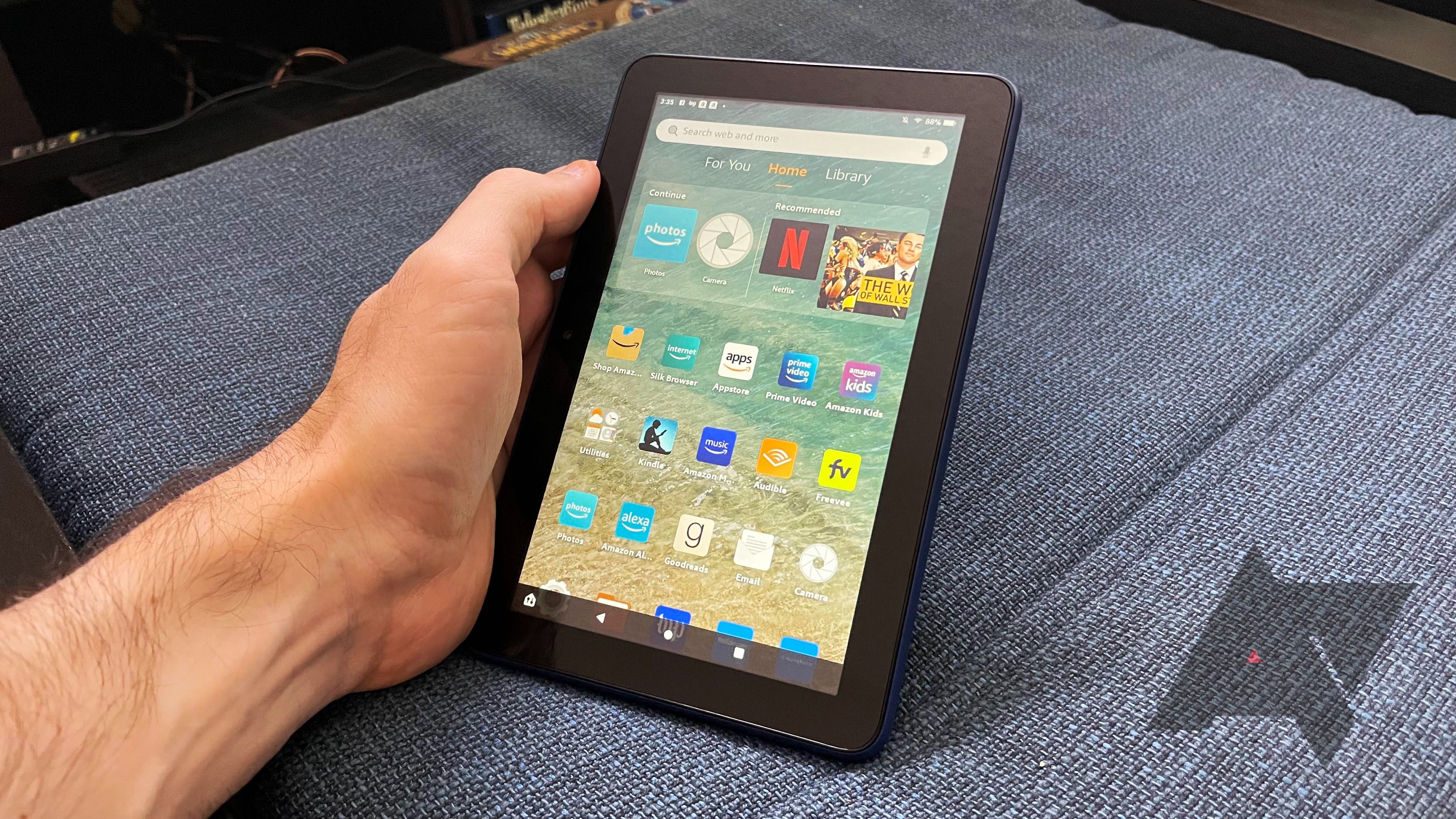 A person is holding a black tablet with their left hand