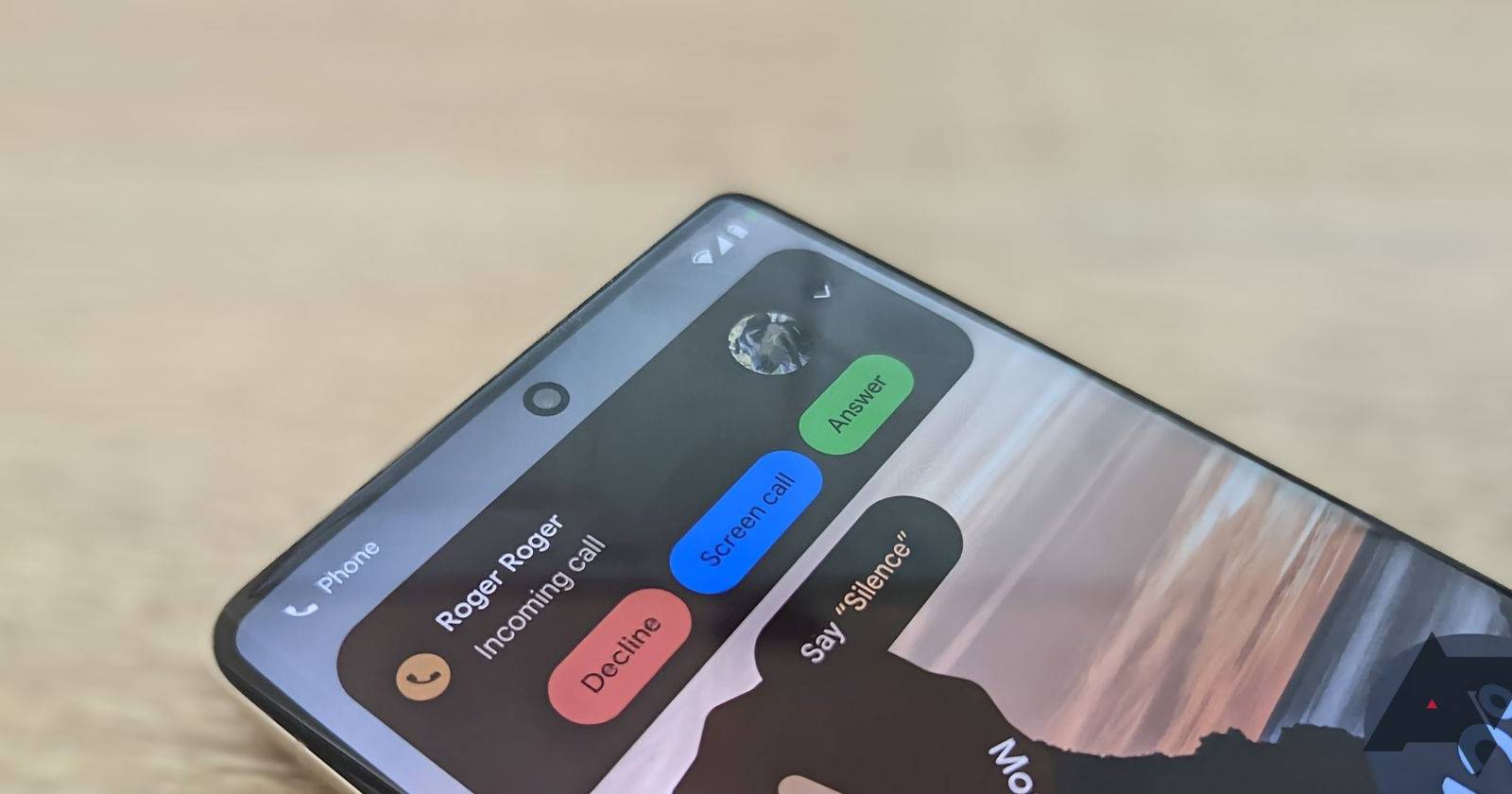 Smartphone receiving call while resting on pale wood surface.