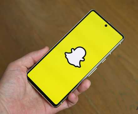 Mão segurando um smartphone com aplicativo Snapchat