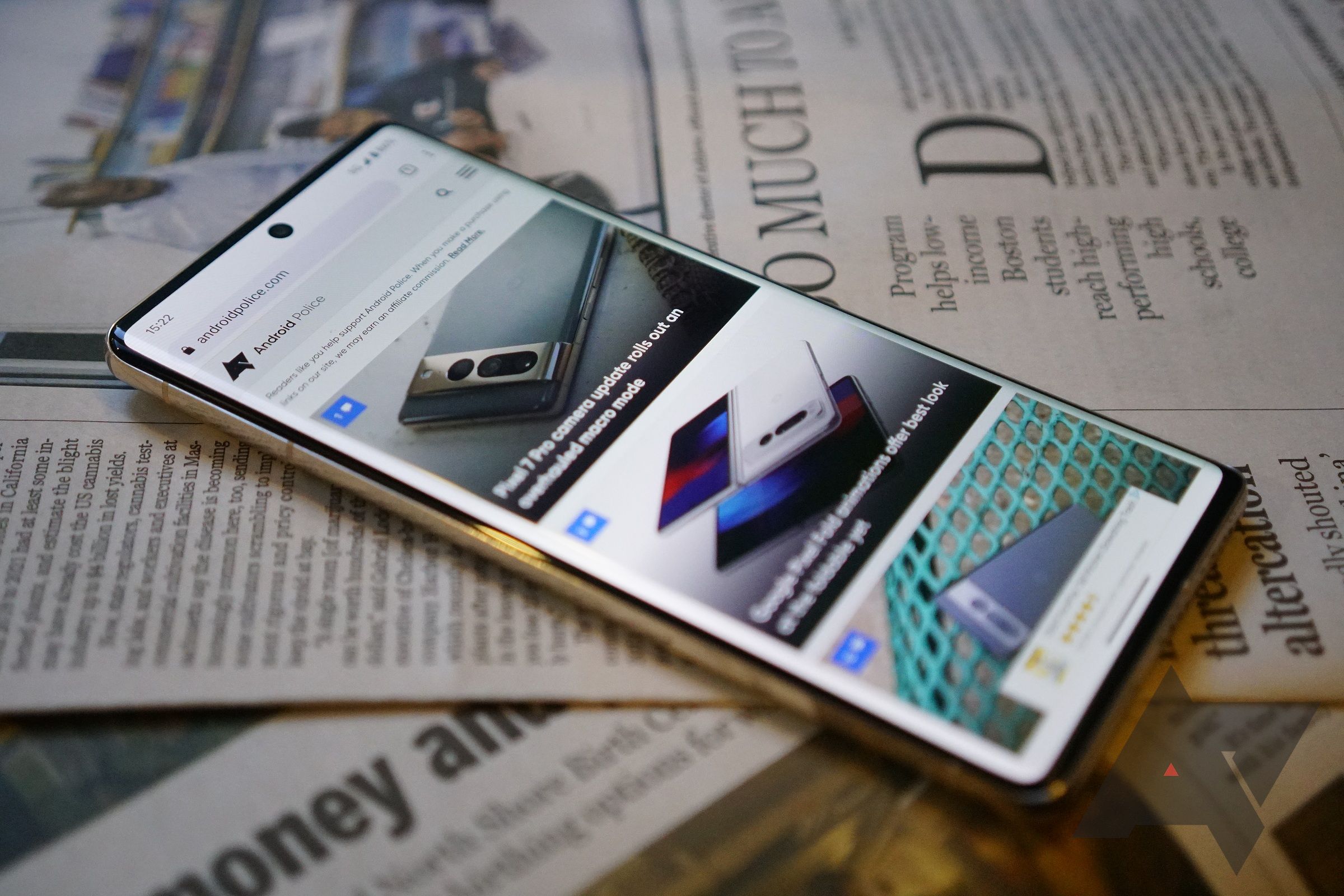 smart phone featuring images on a website resting on top of a newspaper