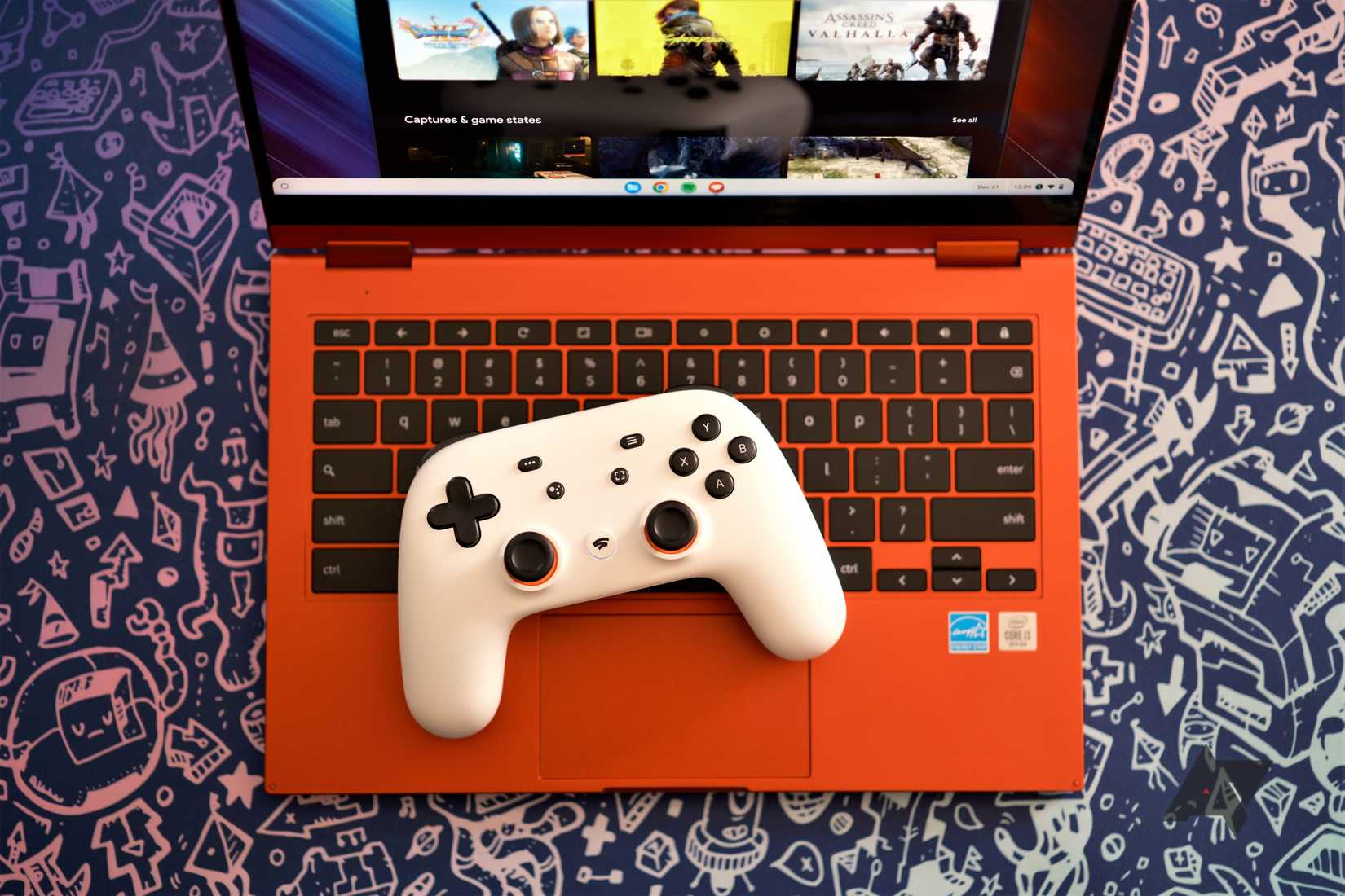 Un controller Google Stadia bianco posizionato sulla tastiera di un Chromebook rosso con un servizio di gioco aperto sullo schermo. Il laptop è posizionato su uno sfondo blu con grafica argentata di immagini di videogiochi.