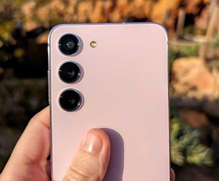 The back of a pink Galaxy S23 with a thumb on the back