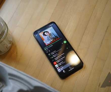 Um telefone com o aplicativo Spotify aberto para uma playlist está sobre uma mesa de madeira.