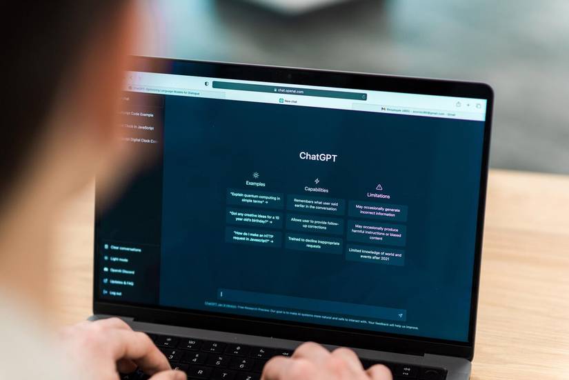 The image shows an over-the-shoulder view of a person using a laptop displaying the ChatGPT interface.