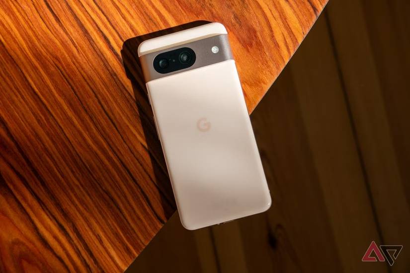 Un Google Pixel 8 bianco appoggiato a faccia in giù su un tavolo di legno.