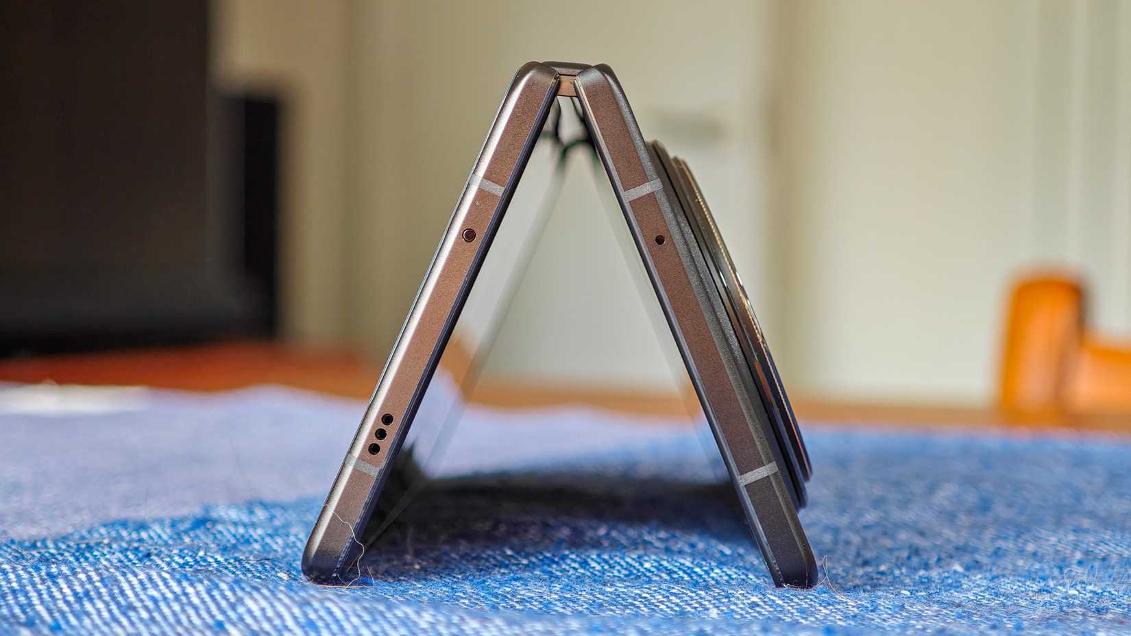 The Vivo X Fold 3 Pro show from the end as it stands on a blue tablecloth in a tent position