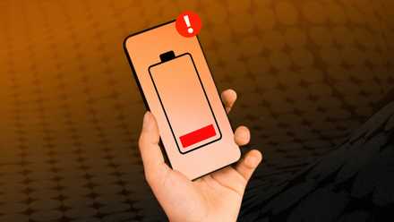 Une main tenant un smartphone avec une icône de batterie faible au centre.