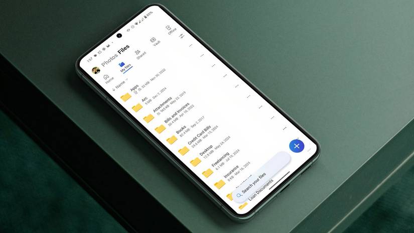An Android phone with a cloud storage app sits atop a gray table.