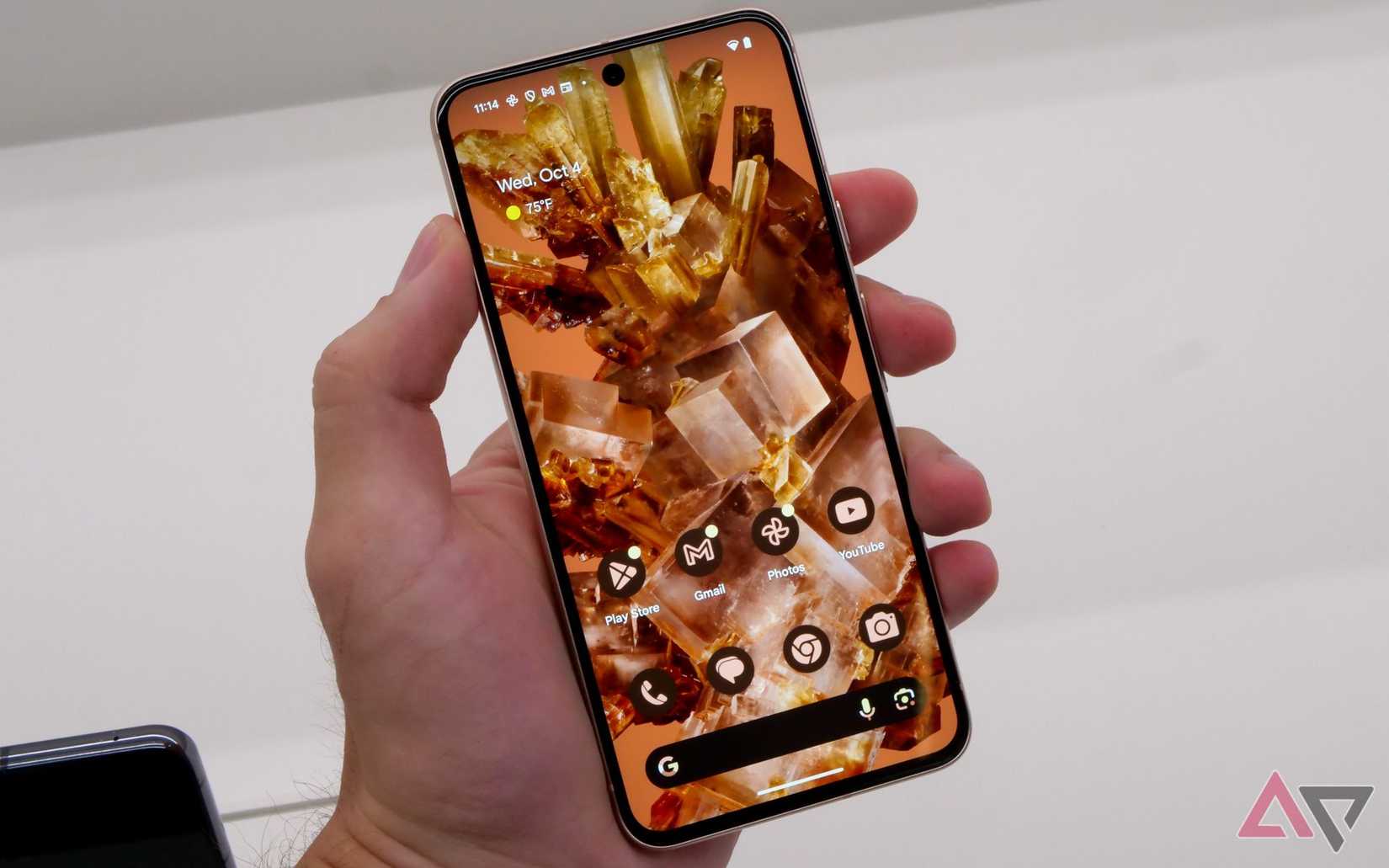 A hand holding a Google Pixel 8 smartphone and showing the home screen