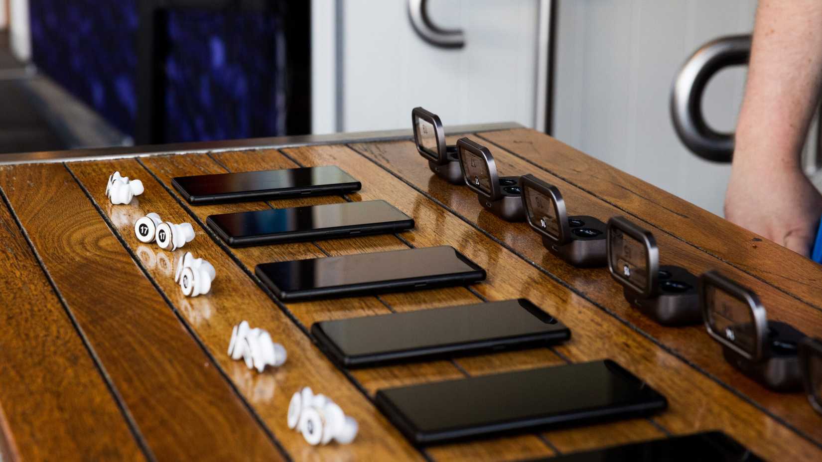 Foto de vários telefones e fones de ouvido colocados em uma superfície de madeira para demonstrar os recursos do Auracast.