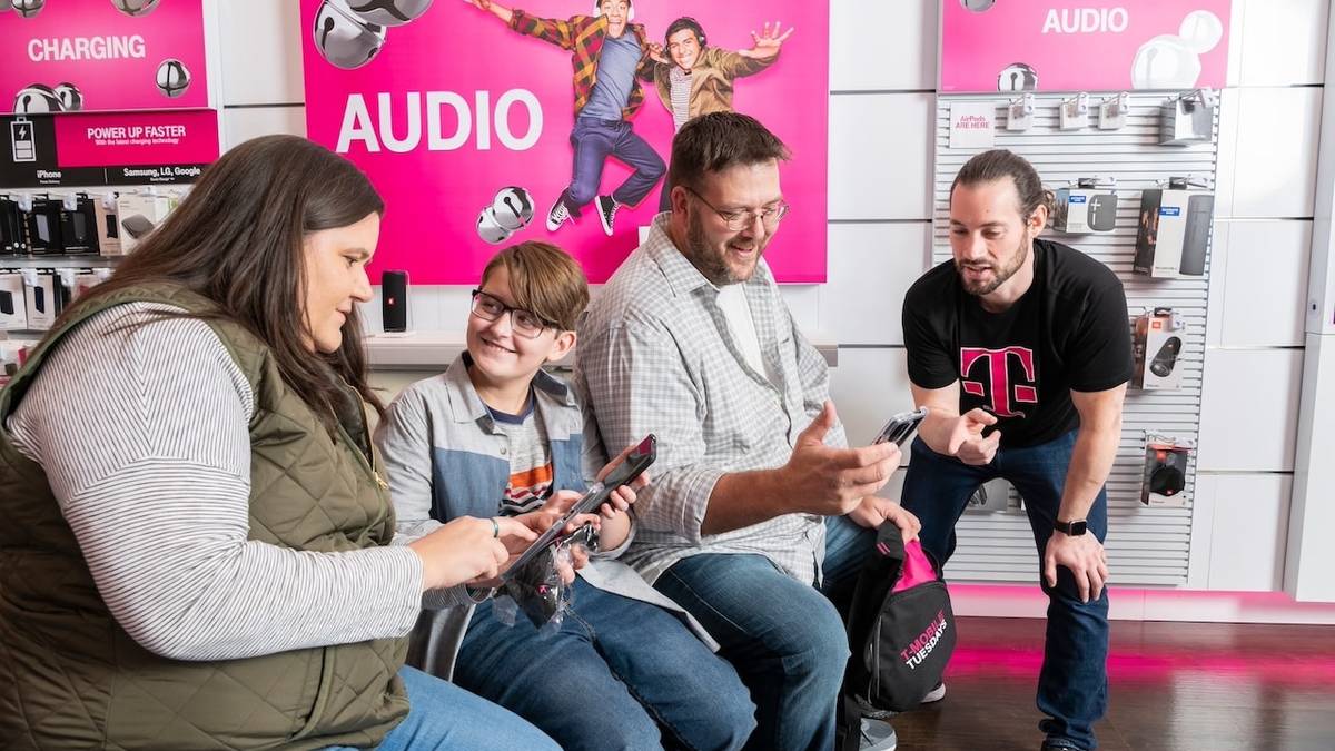 Parents and child holding phones and talking with T-Mobile store representative 