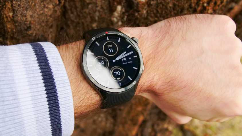 The OnePlus Watch 3 on a wrist next to a tree.