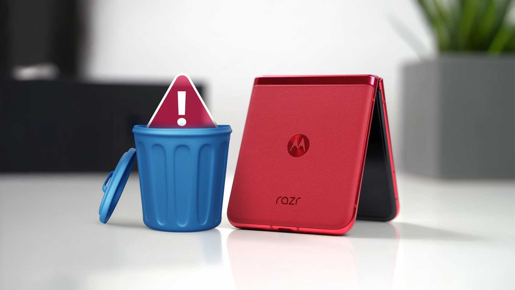 Telefone Motorola vermelho dobrado ao lado de uma pequena lata de lixo azul com sinal de alerta vermelho dentro dele
