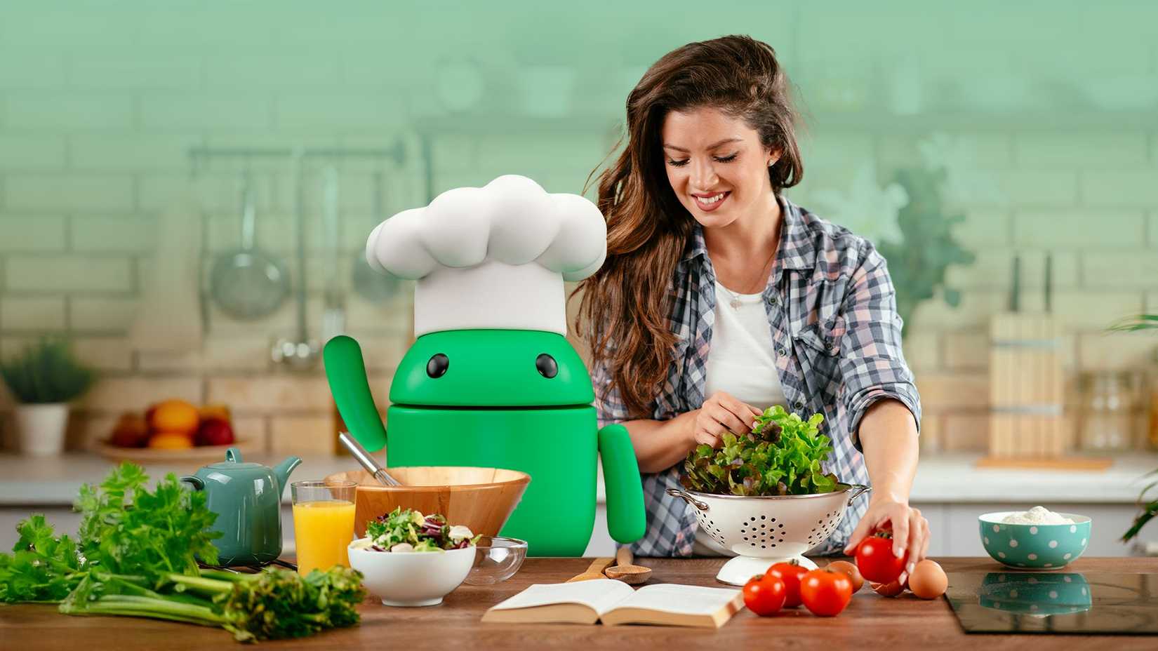 Smiling woman preparing a salad in a kitchen beside the Android mascot wearing a chef hat, surrounded by fresh vegetables and cooking items