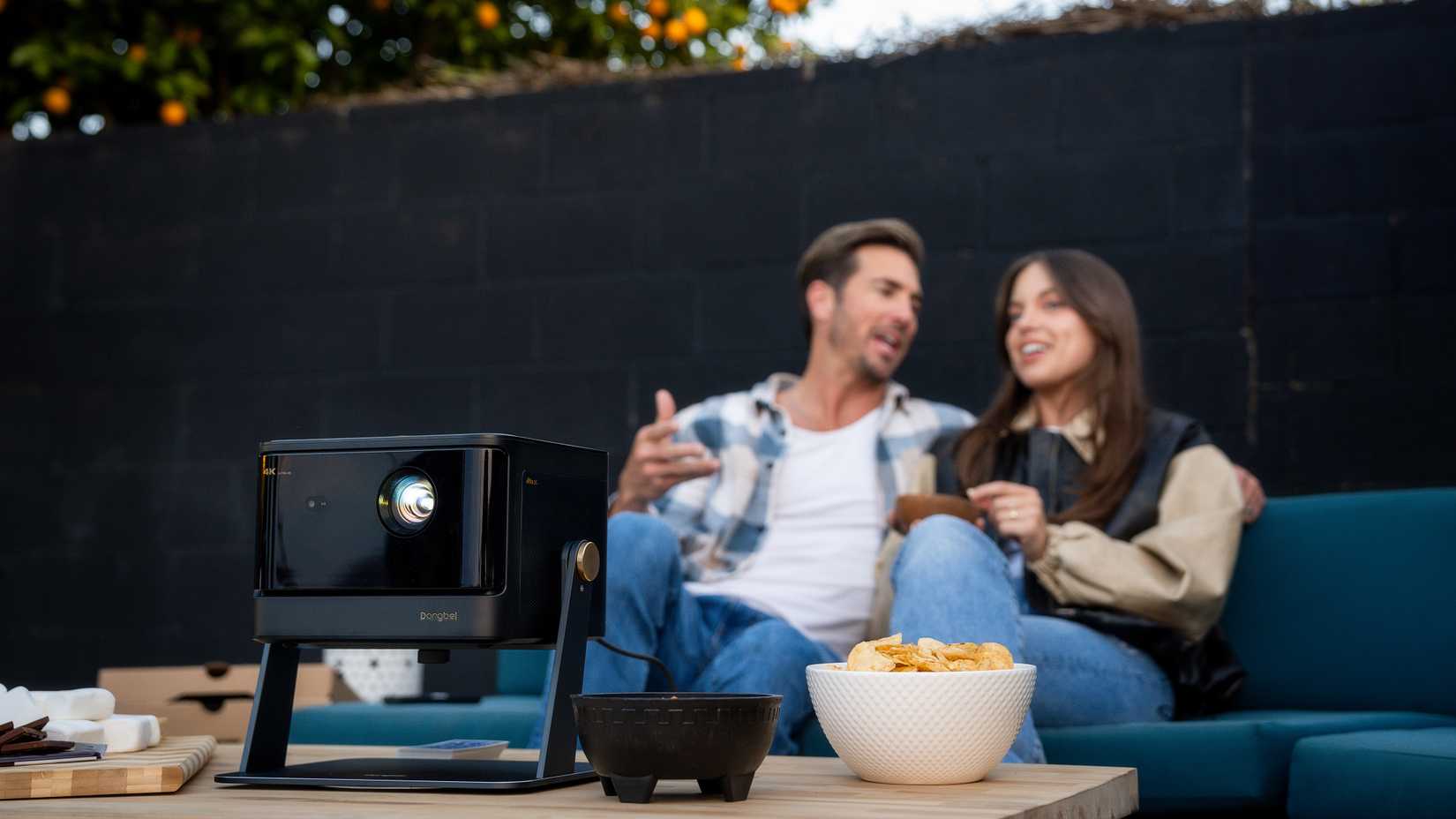 Dangbei DBOX02 on a table with snack with a couple in the background