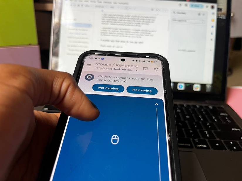 Close up view of hand controlling remote mouse app in front of MacBook laptop
