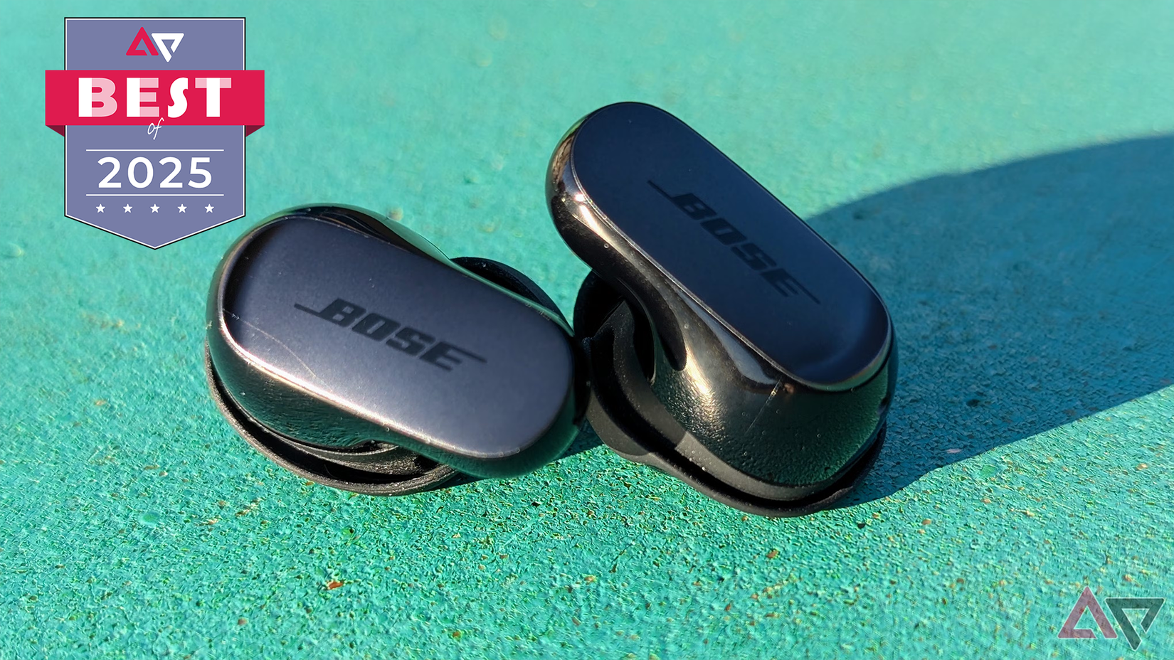 Bose QuietComfort Ultra (2nd Gen) earbuds on a green rock.