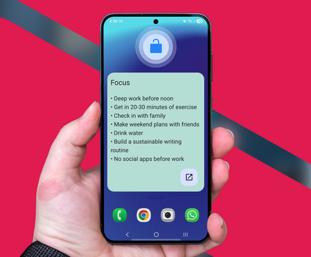Hand holding a smartphone displaying a 'Focus' widget with a list of daily goals on the home screen.