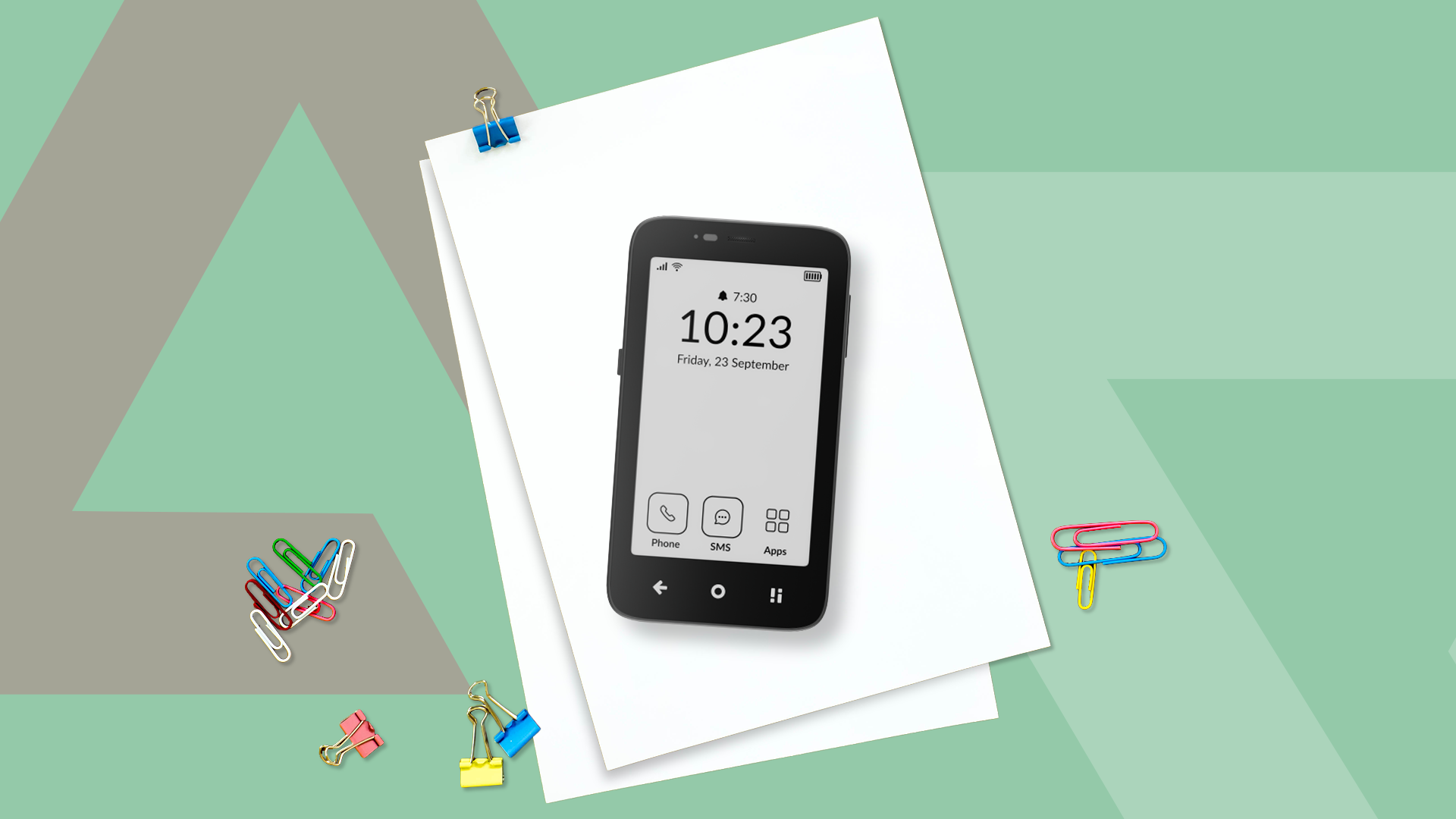 A Mudita Kompakt on a stack of papers surrounded by colorful paper clips on a light green background.