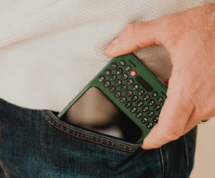 A hand taking a Clicks Communicator out of a pocket