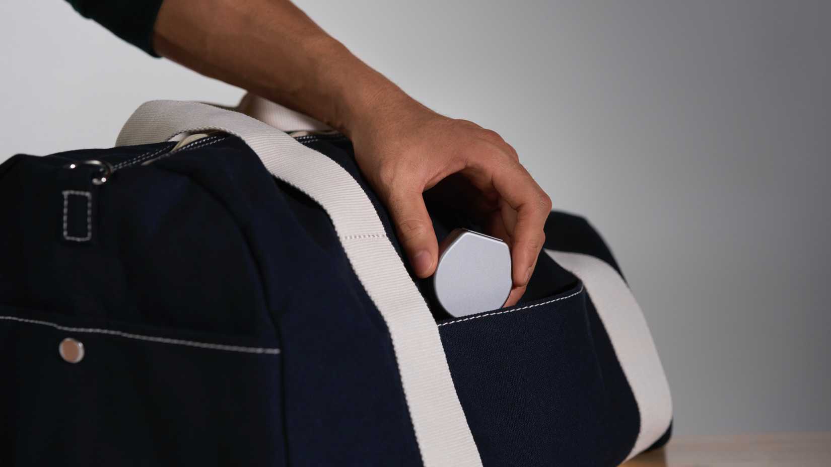 Uma pessoa colocando o estojo de carregamento Oura em uma bolsa