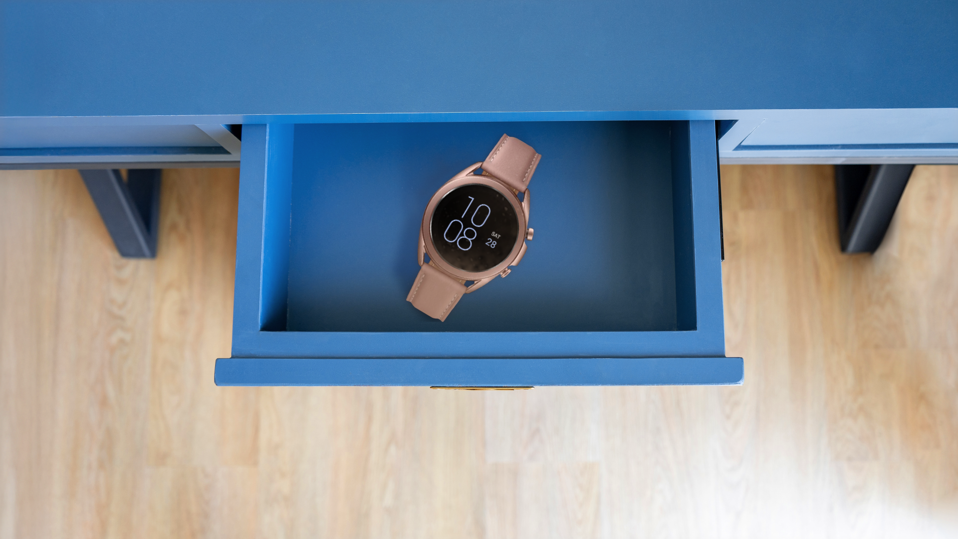 Top-down view of a smartwatch inside an open blue drawer.