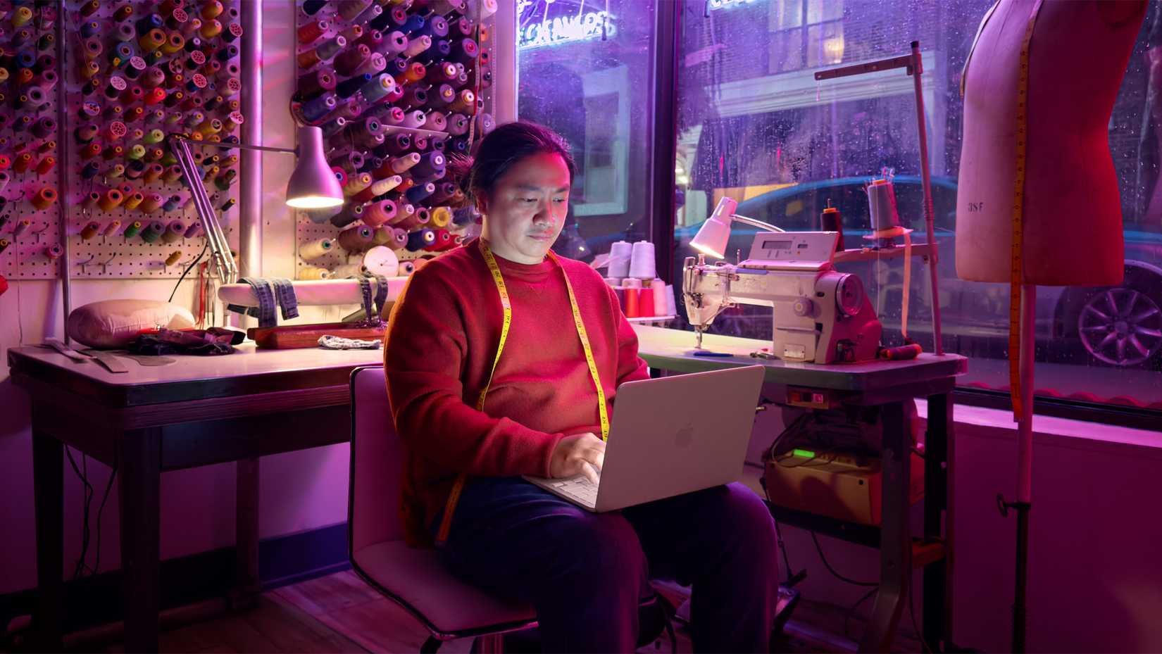 Um designer de moda usa um MacBook Neo em seu estúdio.