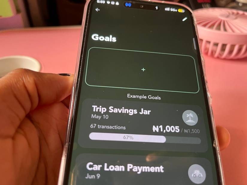 Mano che tiene il telefono visualizzando i campi di immissione per impostare l'obiettivo finanziario
