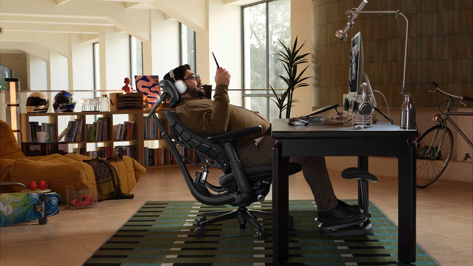 A man reclines in an ergonomic chair while on a video chat on his phone.