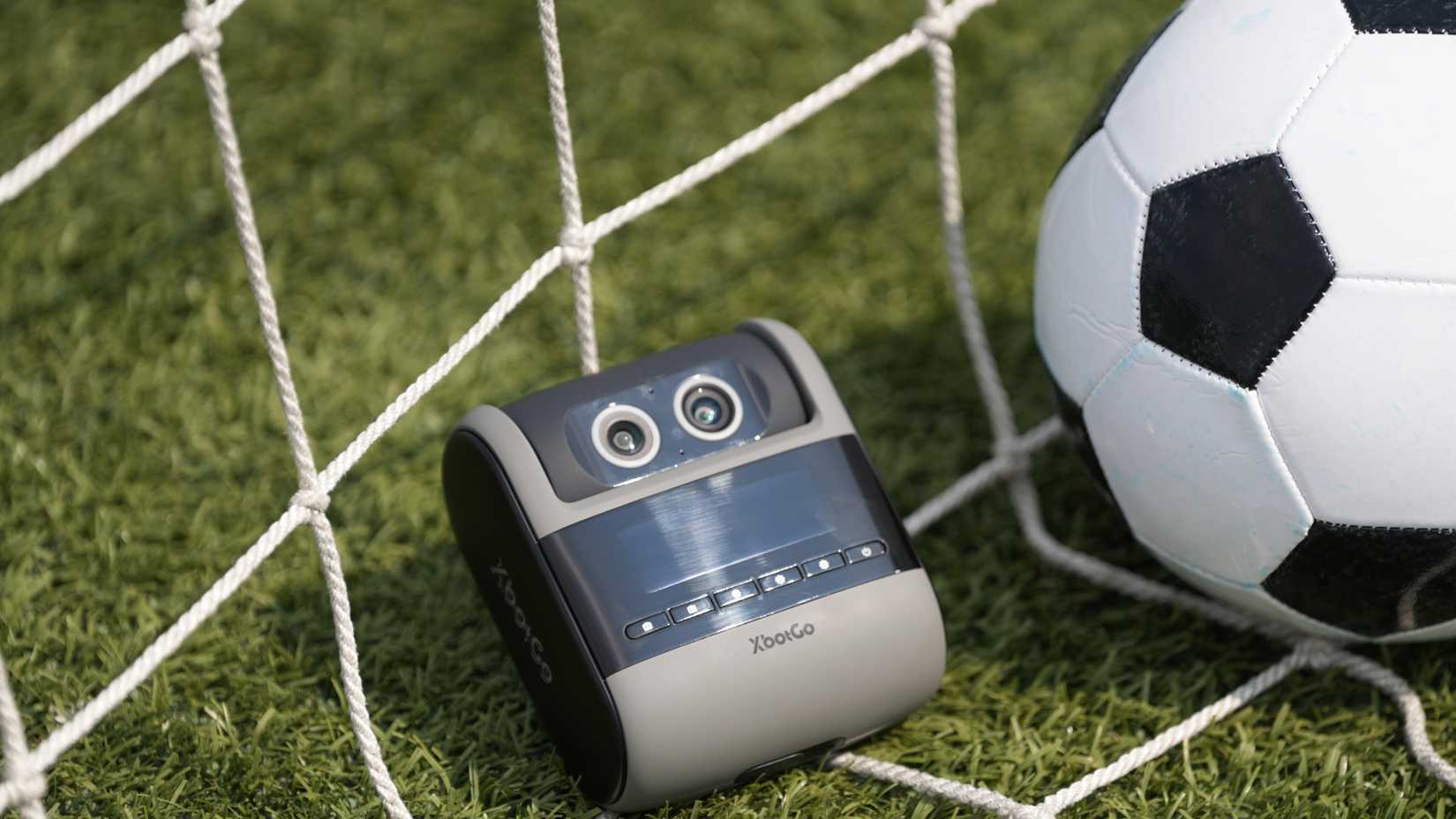 The XbotGo Falcon AI sports recorder next to a soccer ball and goal net.