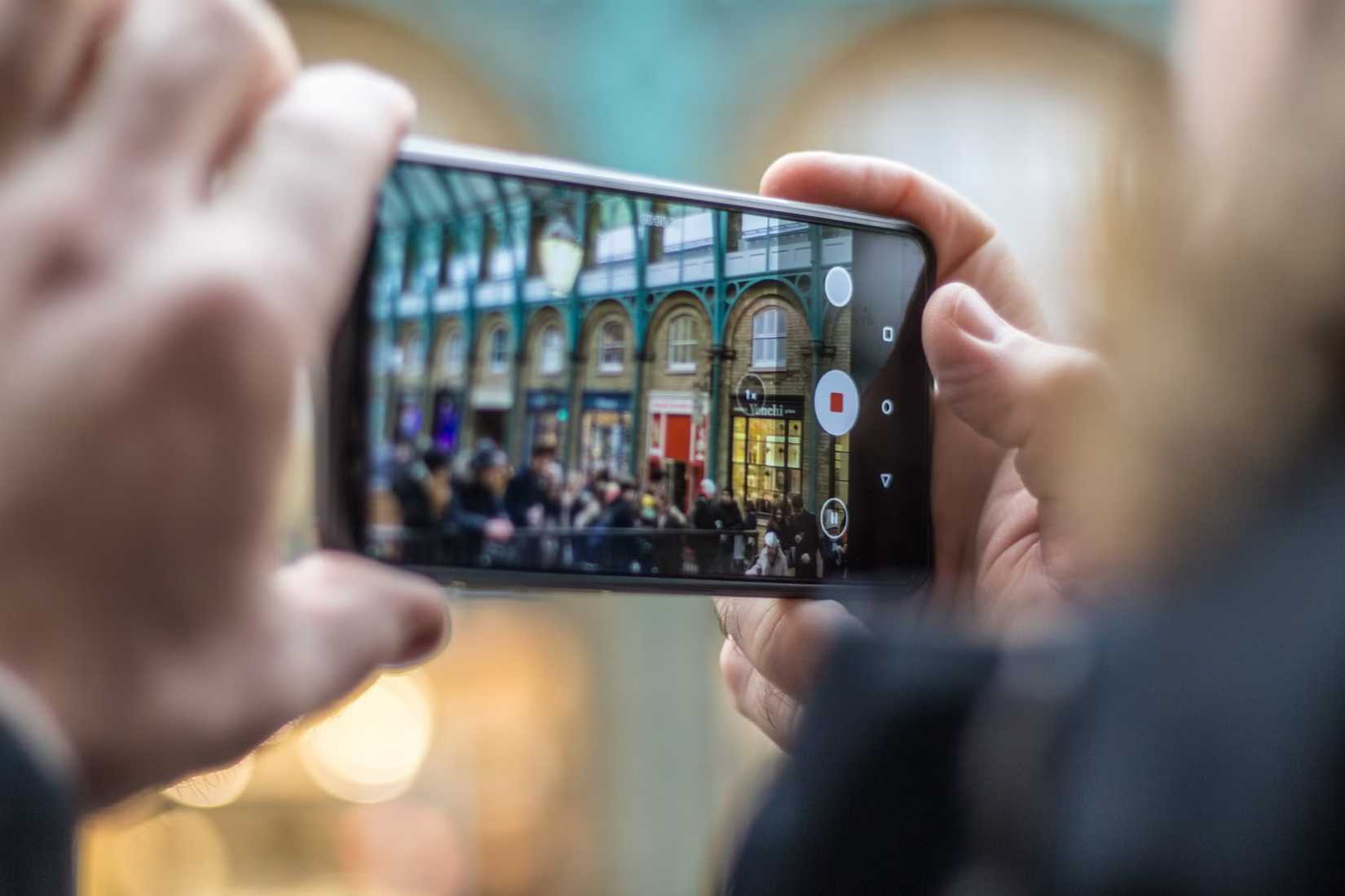 Image of a man's hands holding an Android phone recording video