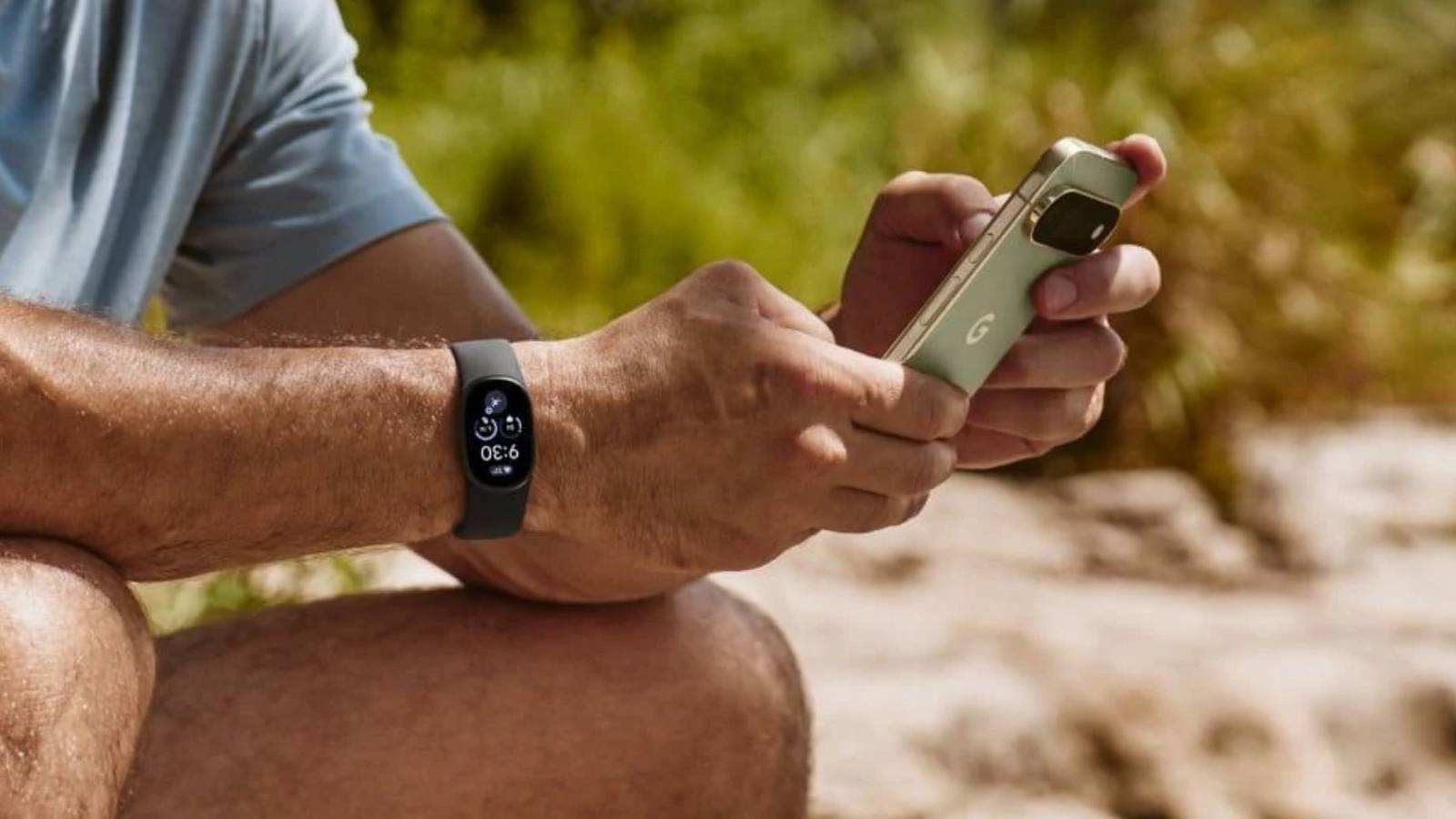 Person wearing Fitbit Edge outdoors with Pixel phone