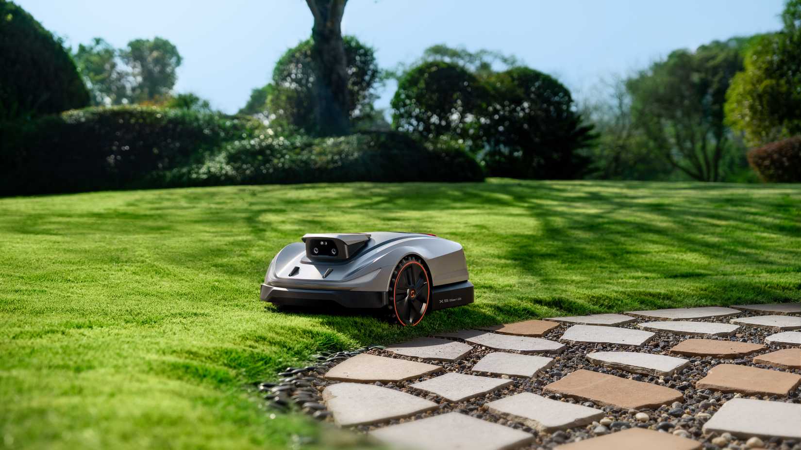 The Sunseeker X5 Gen 2 trimming the edge of the lawn near rock pavers.