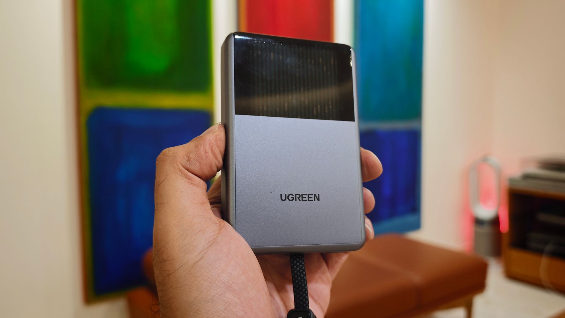 UGREEN Magflow Pro in hand with liquid cooling animation and paintings in the background