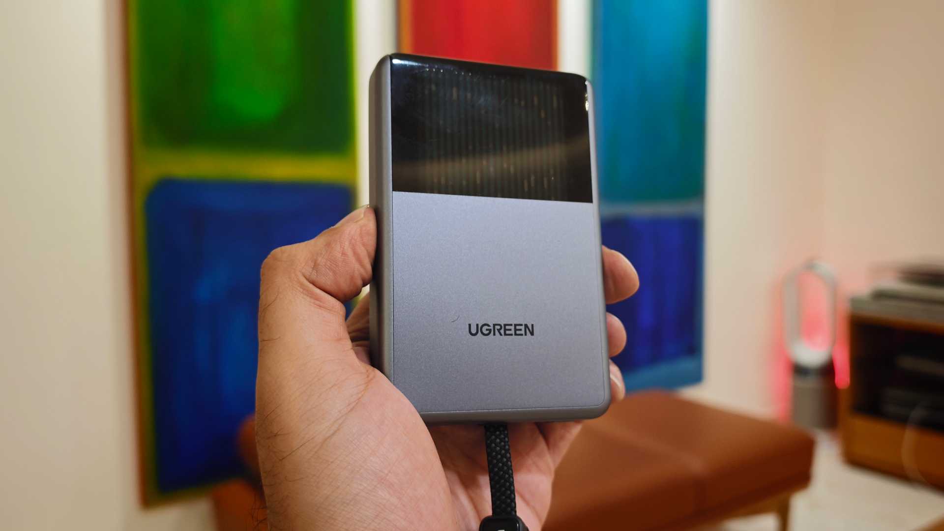 UGREEN Magflow Pro in hand with liquid cooling animation and paintings in the background