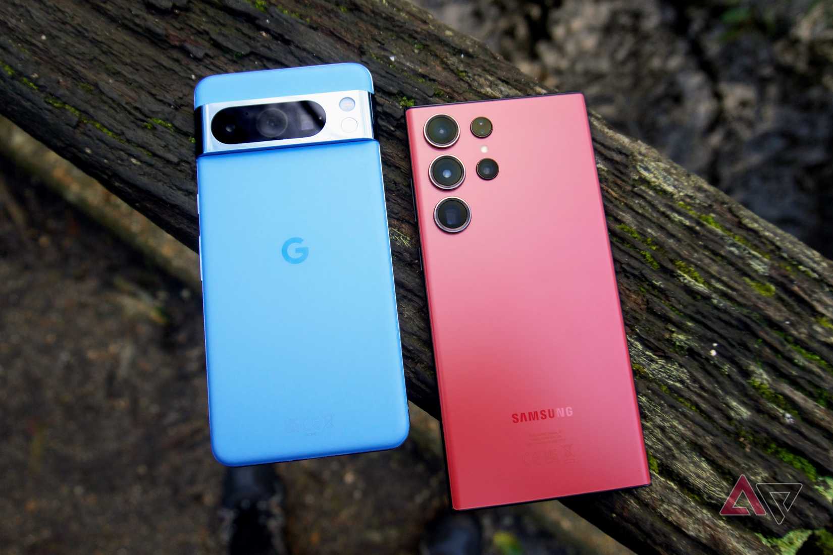 O Pixel 8 Pro e o Galaxy S23 Ultra deitados de bruços em um tronco