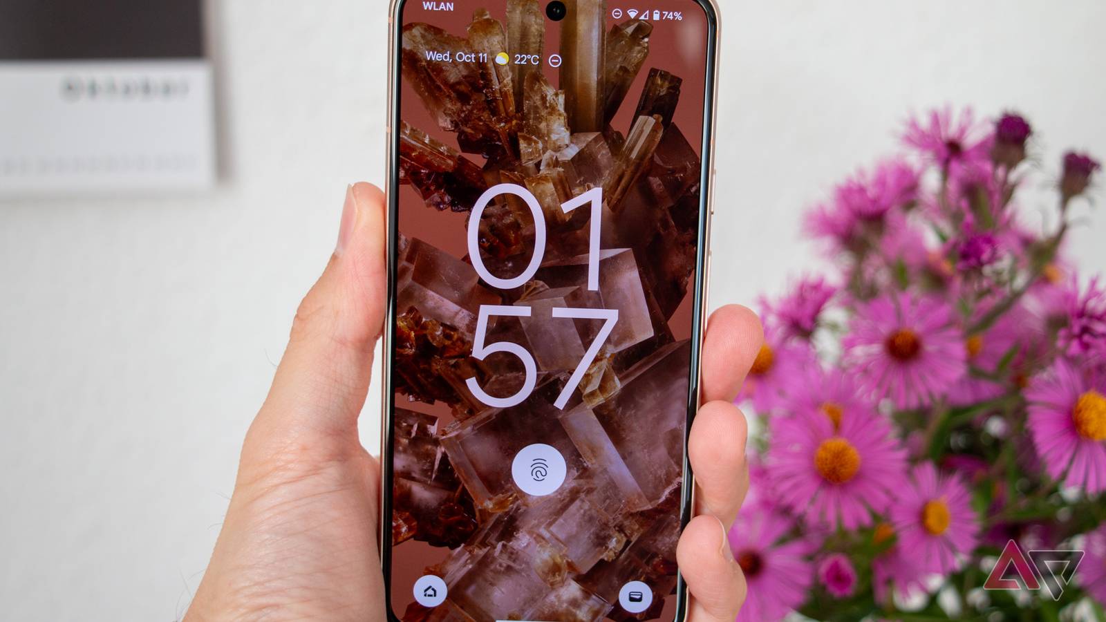 Hand holding a Pixel 8 phone showing a lock screen.