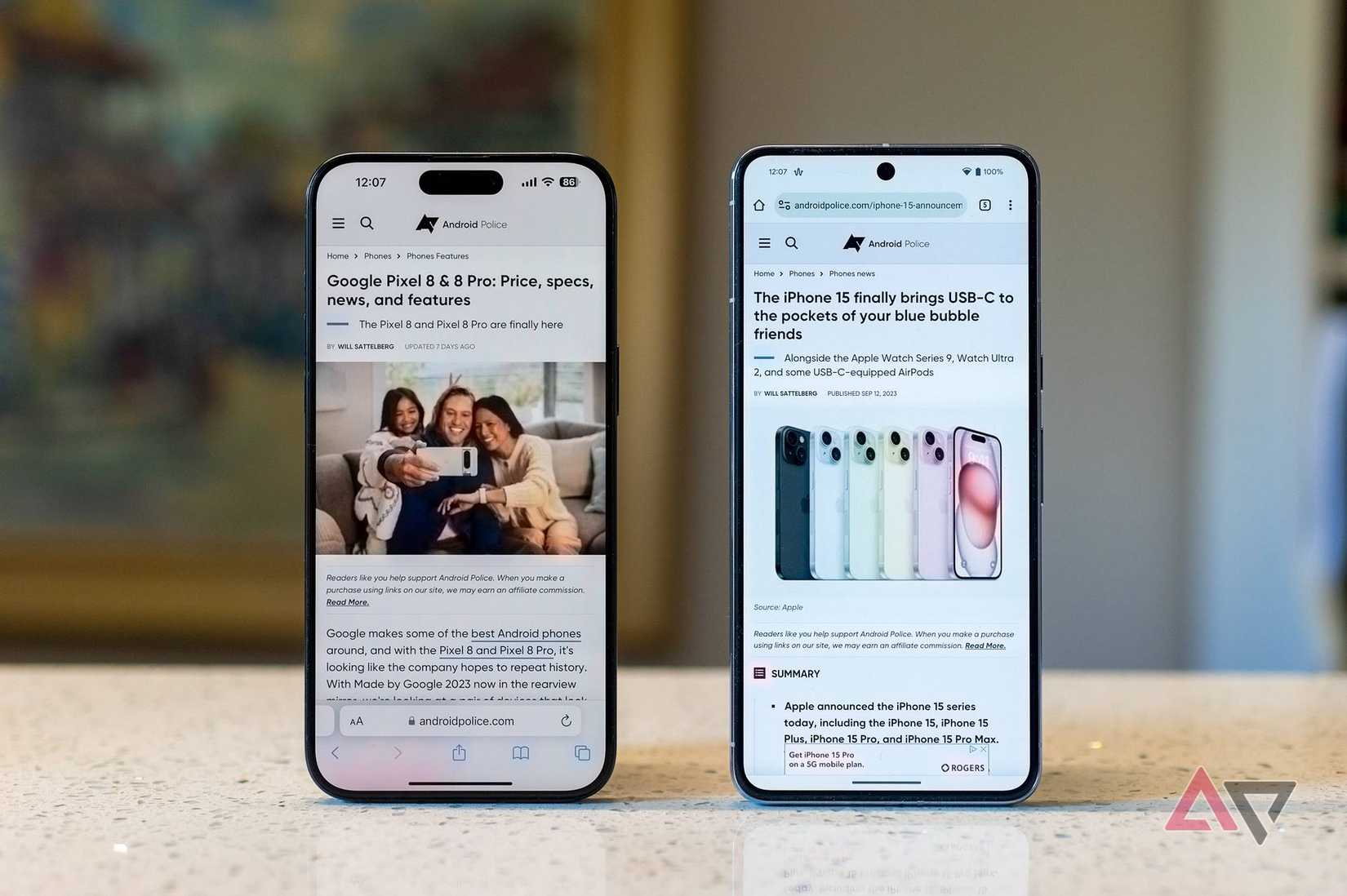 The iPhone 15 Pro Max next to the Google Pixel 8 Pro on a kitchen counter, both displaying the Android Police website
