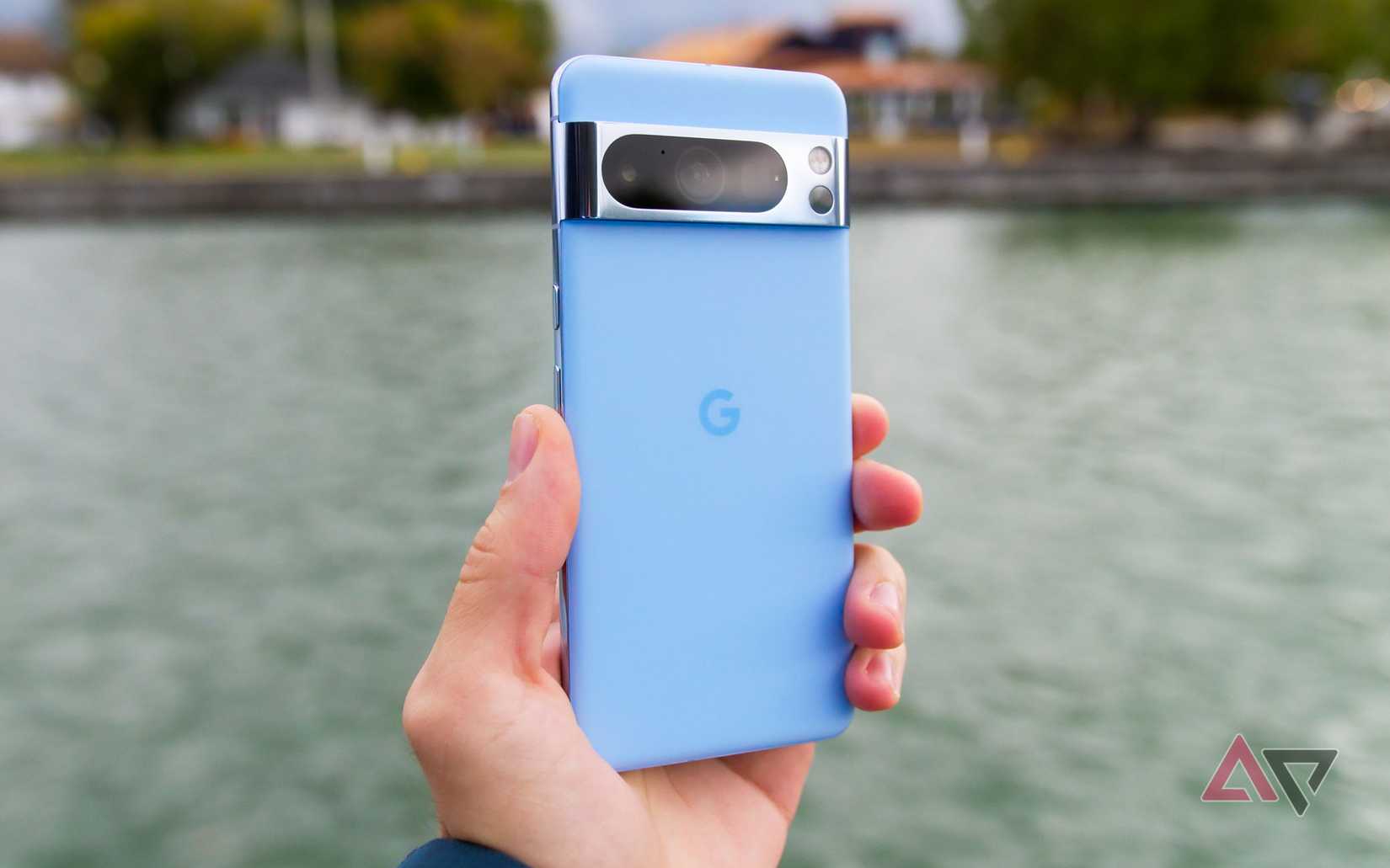 Uma foto de um Pixel 8 Pro azul sendo segurado em frente a um rio
