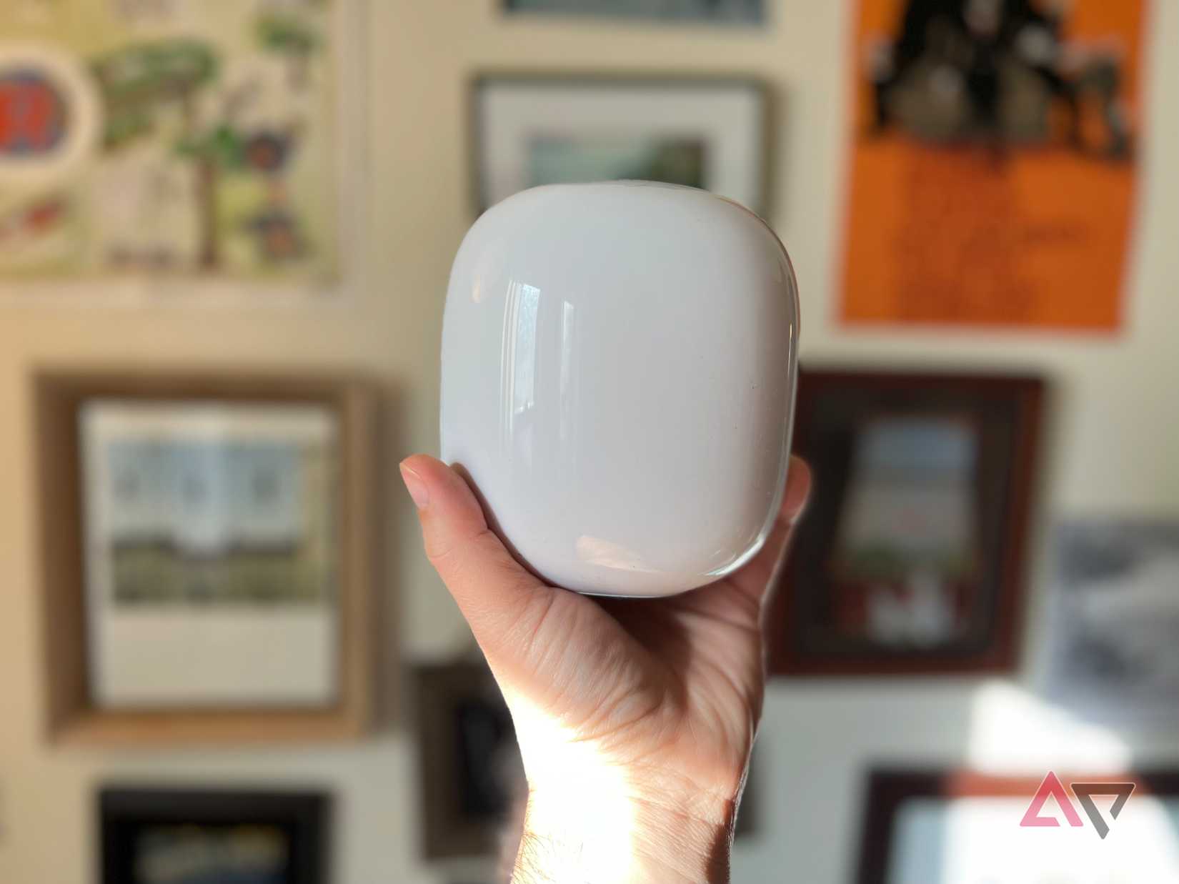 Segurando o Google Nest Wifi Pro com fotos e arte em segundo plano