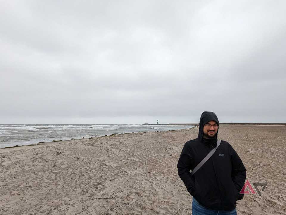 man in black rain jacket standing on beach under cloudy sky