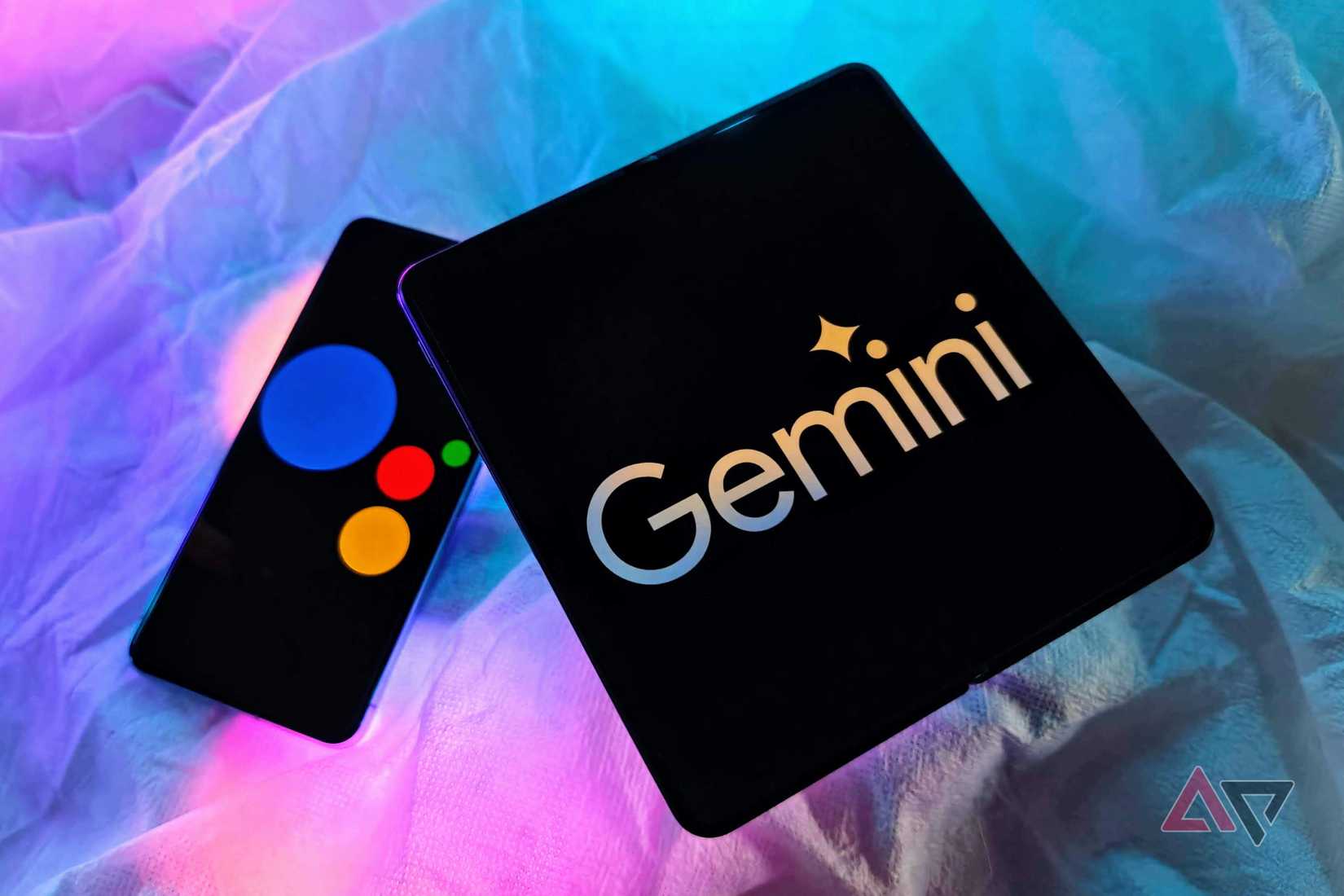 OnePlus Open with Google Gemini logo and Pixel 8 Pro with Google Assistant logo on a table with RGB lights