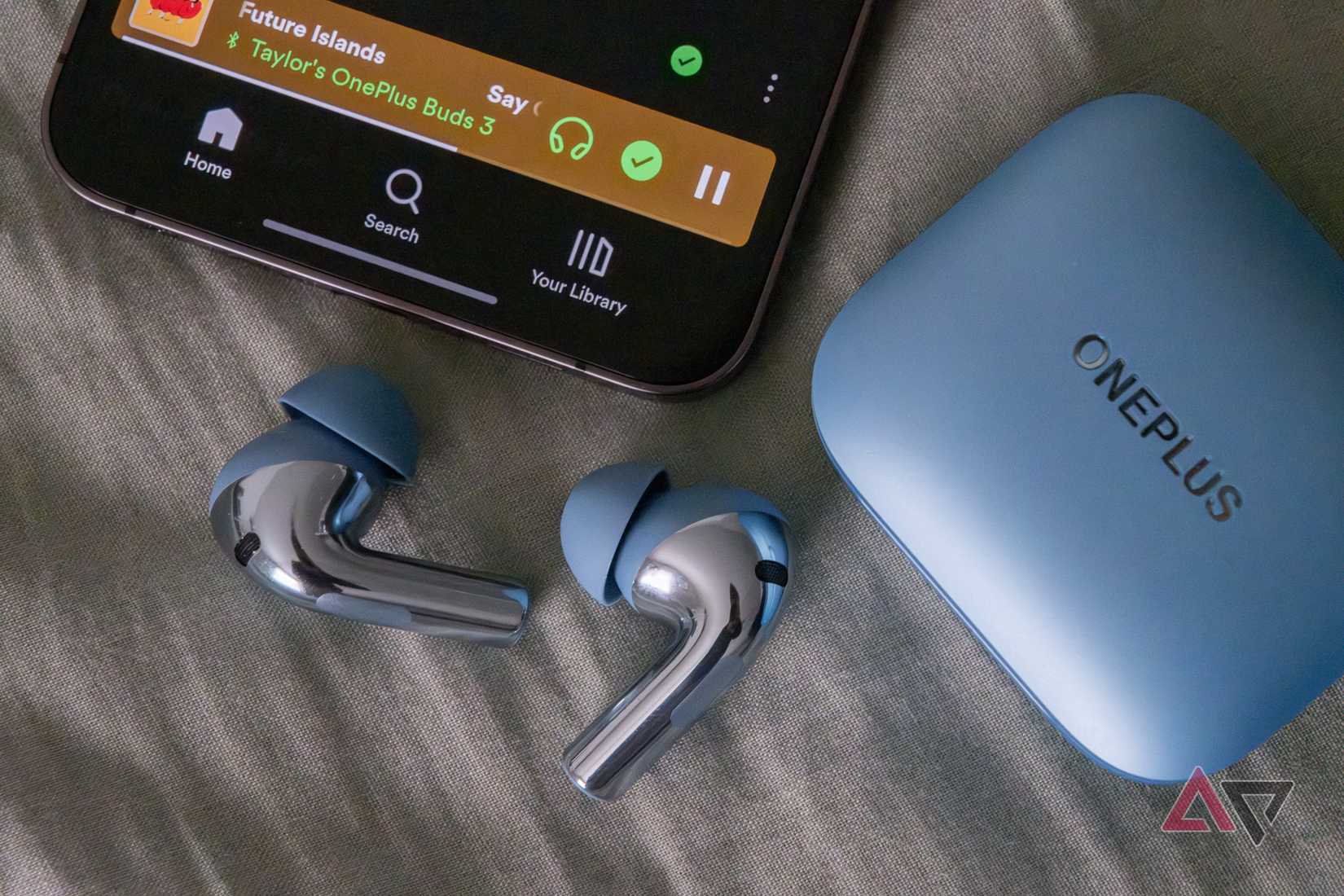 Earbuds next to a phone running the Spotify app