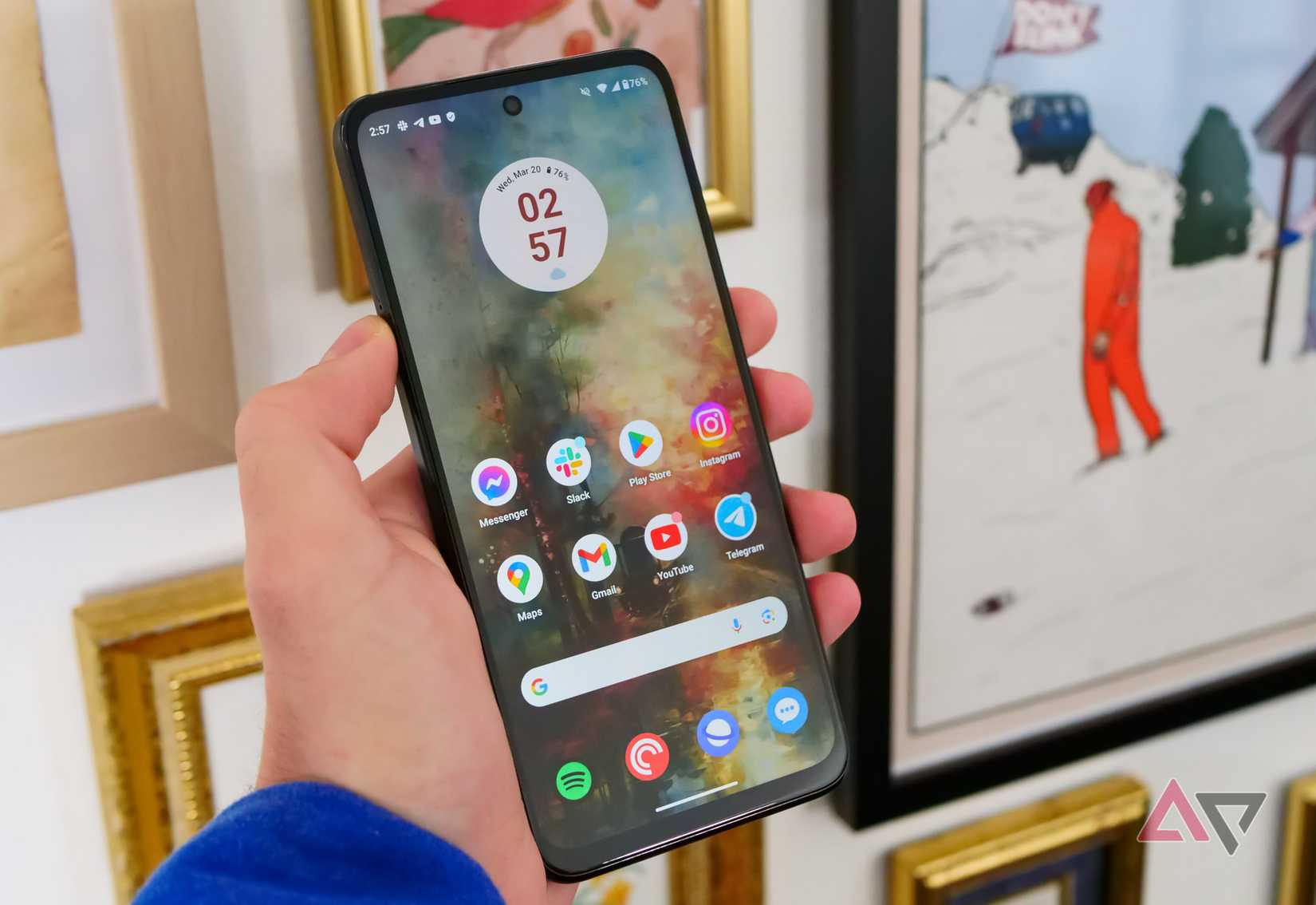 Il Moto G Power (2024) è in mano accanto alle cornici per foto.