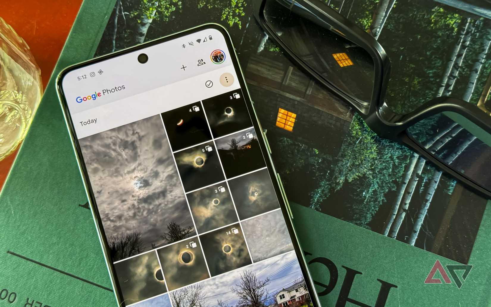 O Pixel 8 Pro rodando o Google Fotos sobre um livro ao lado dos óculos Eclipse.