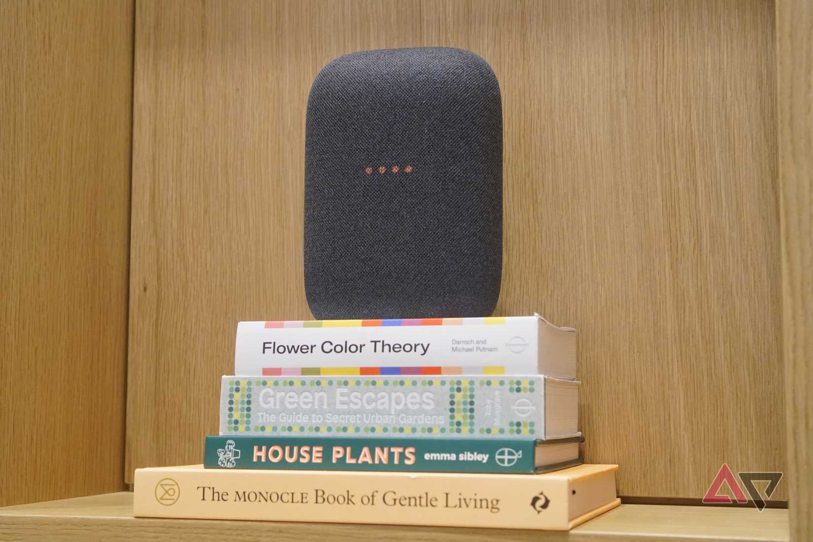 Un altoparlante smart Google Nest Audio di colore grigio, sopra una pila di libri.