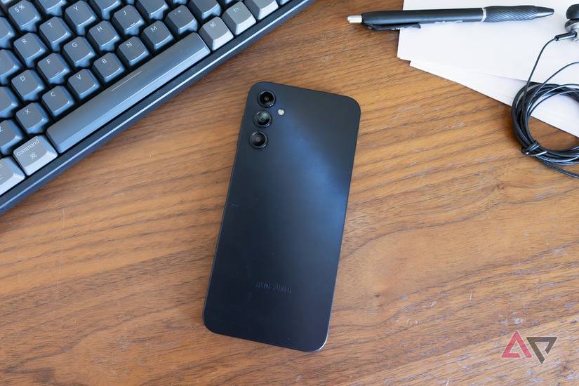 Um telefone Bark virado para baixo em uma mesa ao lado de um teclado e fones de ouvido.