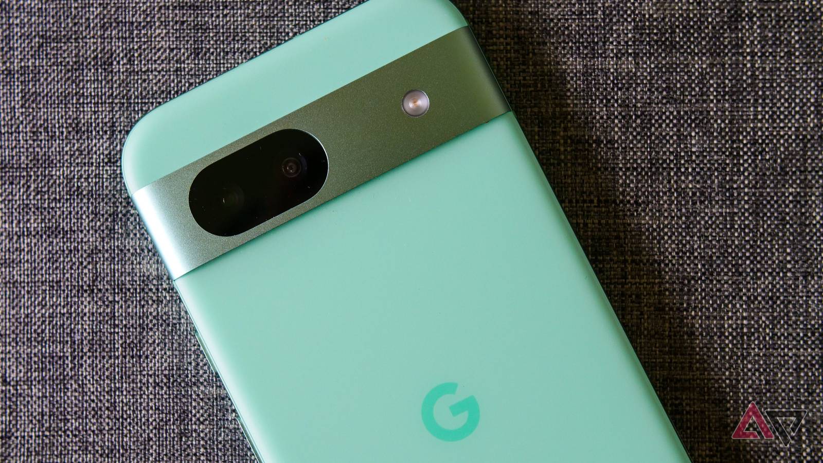 A closeup on the Pixel 8a lying on gray fabric.