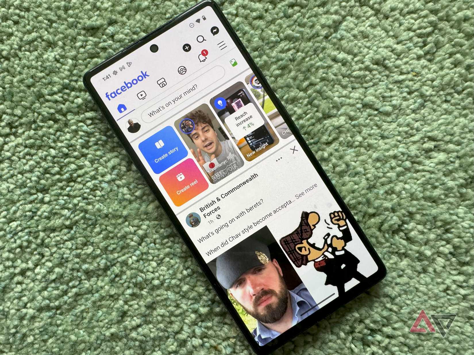Un telefono Pixel su un tappeto verde con l'app Facebook aperta.