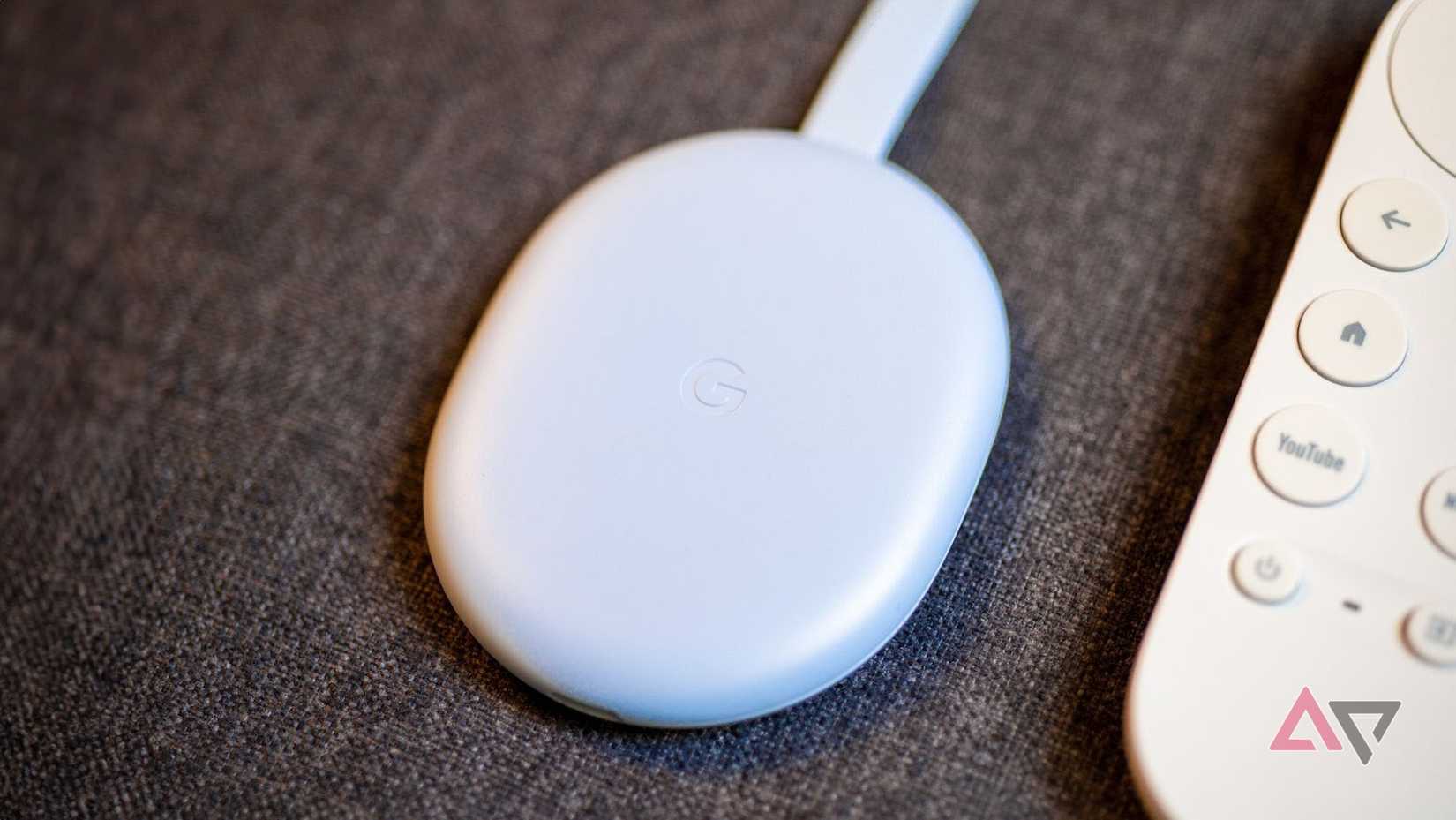 O Chromecast com Google TV HD ao lado do controle remoto em um sofá.